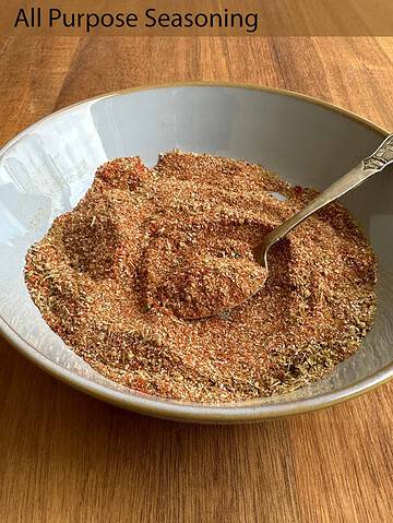 Blend of spices in a light blue bowl with an antique spoon on a wooden table