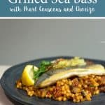 Grilled sea bass on a bed of pearl couscous with chorizo, garnished with a lemon slice and fresh herbs.