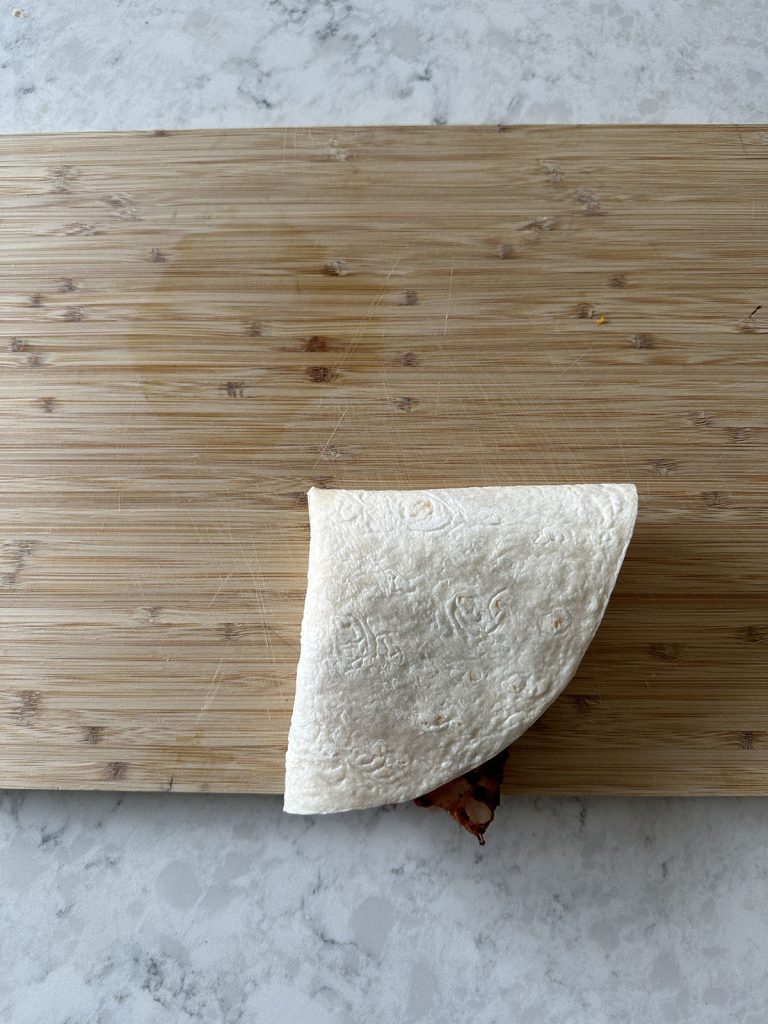 A folded wrap on a wooden cutting board