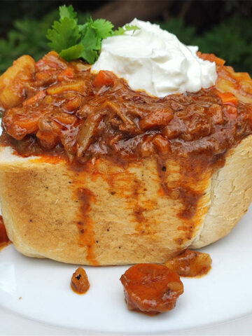 South African bunny chow, a hollowed-out ¼ loaf of bread filled with beef curry, topped with a dollop of yogurt and cilantro.