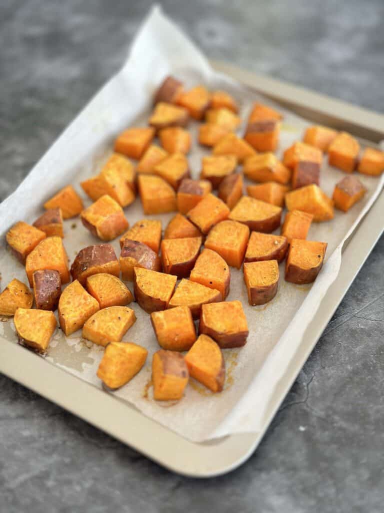 Roasted sweet potato cubes on baking sheet.