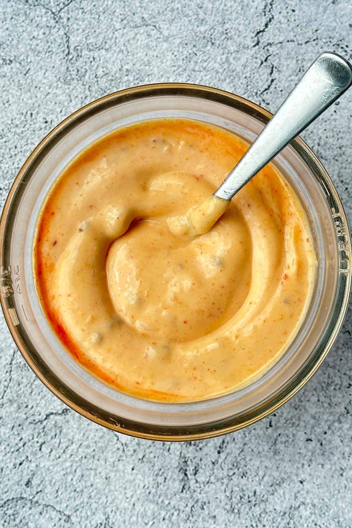 Chili mayonnaise fully mixed in a glass bowl with a spoon.