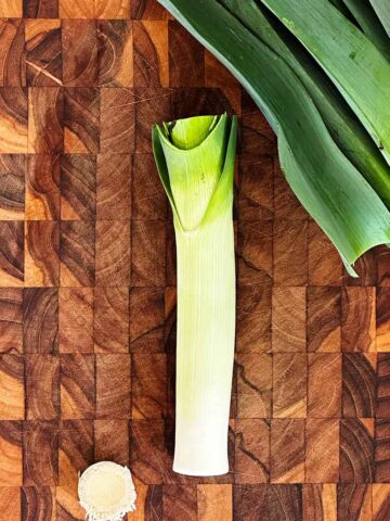 Trim white and green leek stalks by cutting off root and dark tops