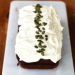 A loaf of pumpkin bread topped with vanilla cream cheese frosting