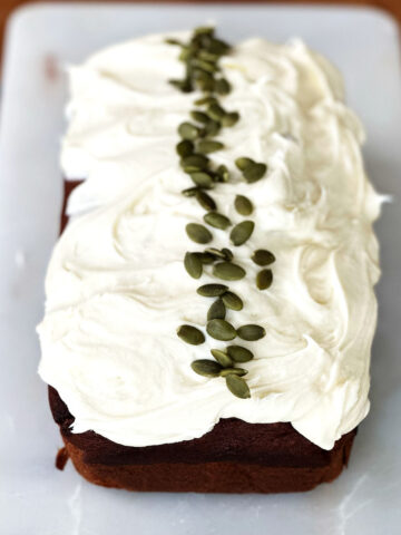 A loaf of pumpkin bread topped with vanilla cream cheese frosting