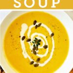 White bowl of cauliflower and pumpkin soup topped with Greek yoghurt and pepitas, served with toasted bread on the side.