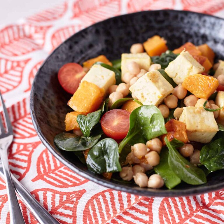 Golden baked halloumi and roasted pumpkin salad with chickpeas, cherry tomatoes, baby spinach, and snow peas, drizzled with lemon honey dressing.