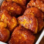 Pumpkin fritters or pampoenkoekies in a baking dish covered with caramel sauce.
