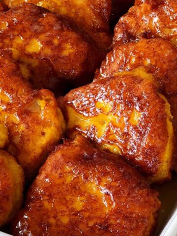 Pumpkin fritters or pampoenkoekies in a baking dish covered with caramel sauce.