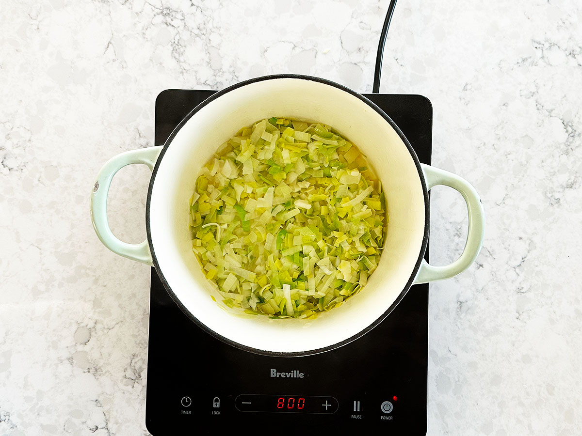 Sautéing onion, garlic, and sliced leek in butter in a large pot as the flavour base for cauliflower and pumpkin soup.