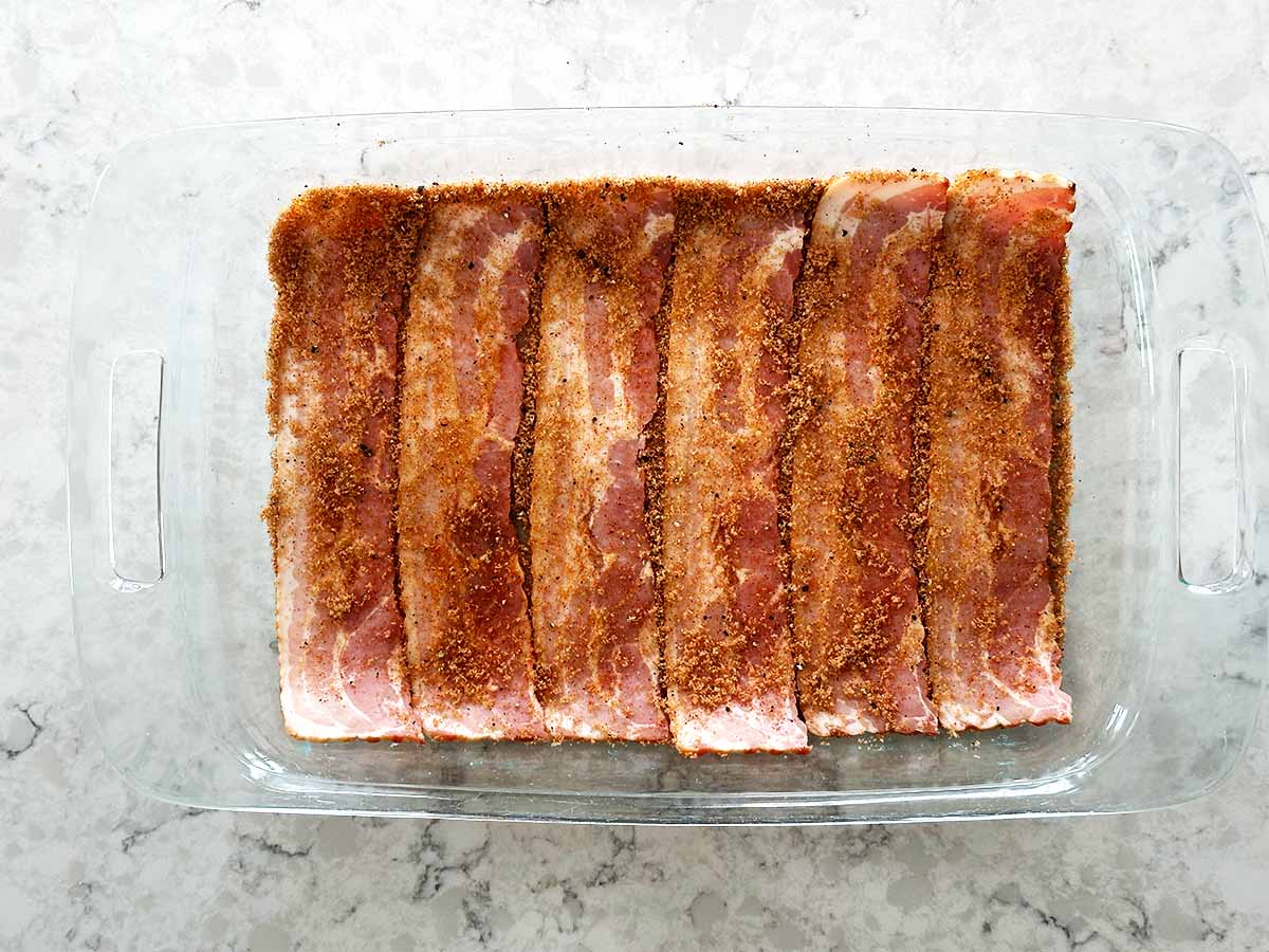 Bacon slices coated with brown sugar mixture for candied bacon recipe.