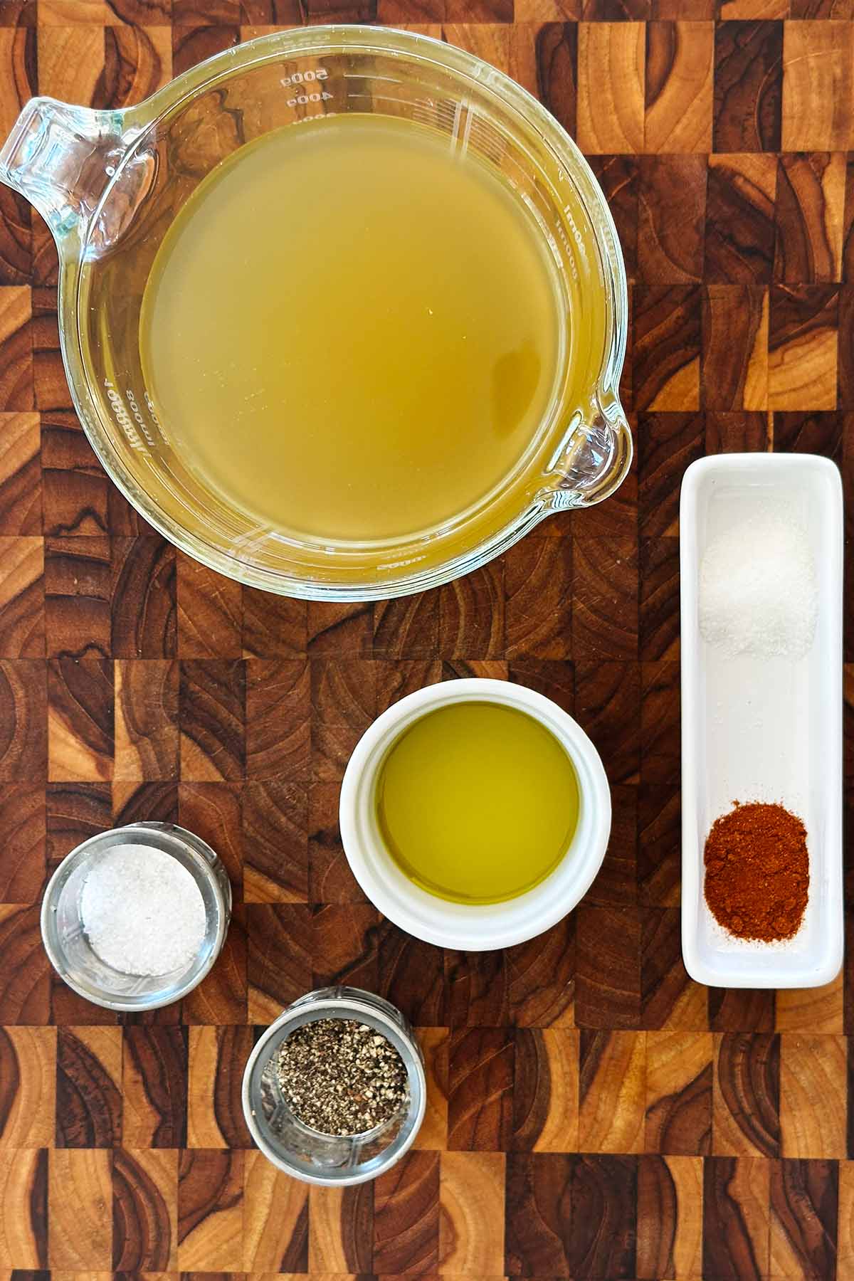 Ingredients measured out for butternut squash tomato soup, including vegetable stock, smoked paprika, salt, and cream.