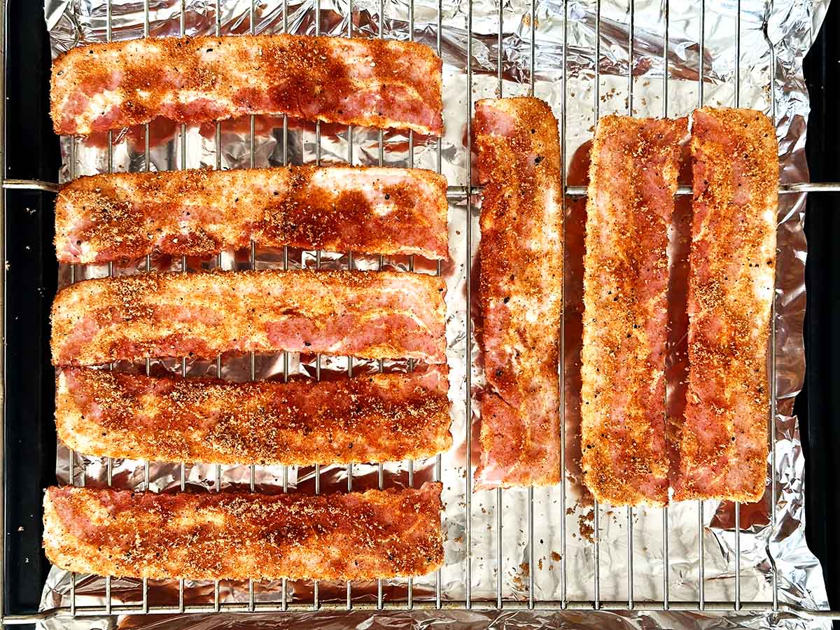 Brown sugar coated uncooked bacon arranged in single layer on wire rack for candied bacon.