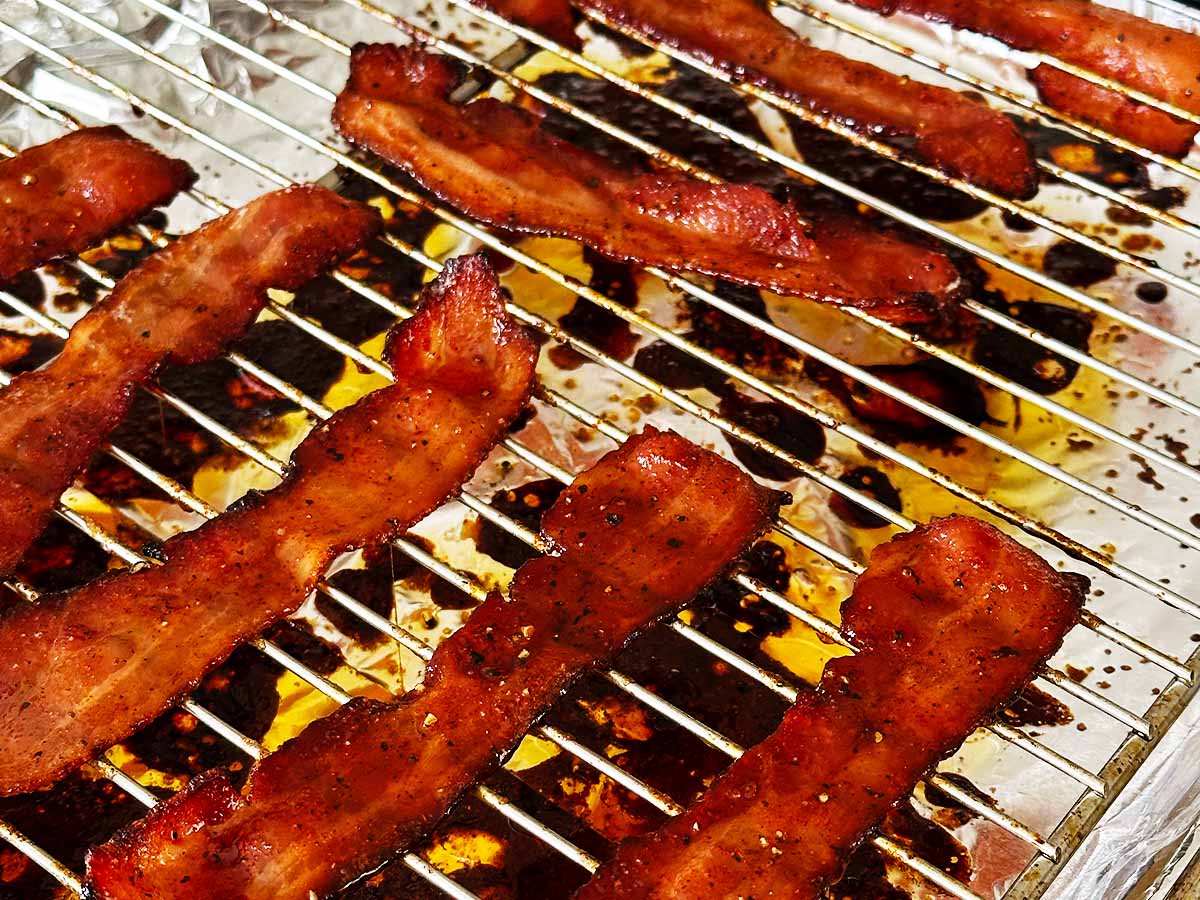 Candied streaky bacon on roasting rack on a foil lined baking sheet - cooling.