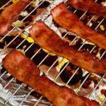 Candied streaky bacon on roasting rack on a foil lined baking sheet.