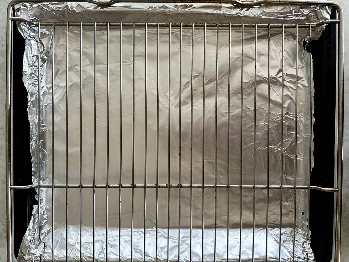 Prepared oven tray lined with foil with a roasting rack set on top, for candied bacon.