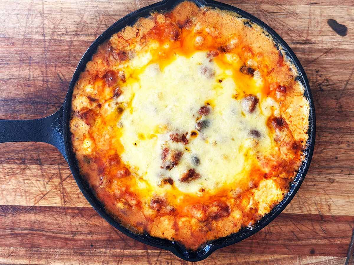 Baked chili cream cheese dip golden and bubbly in skillet.