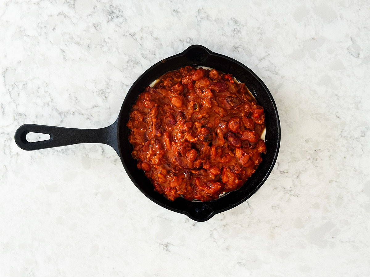 Layer of canned chili over cream cheese in skillet.
