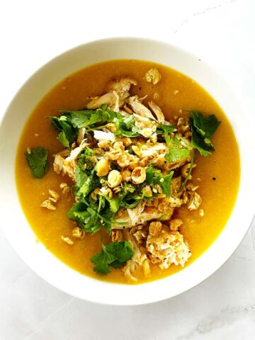 Creamy Moroccan pumpkin soup topped with shredded chicken, fresh coriander, and crushed chickpeas in a white bowl.A warm and creamy Moroccan pumpkin soup made from butternut squash and topped with tender shredded chicken and crushed chickpeas. This easy Moroccan chicken soup recipe is lightly spiced with Moroccan spices and brightened with preserved lemon for authentic flavour. Perfect Moroccan butternut squash soup for quick weeknight dinners.