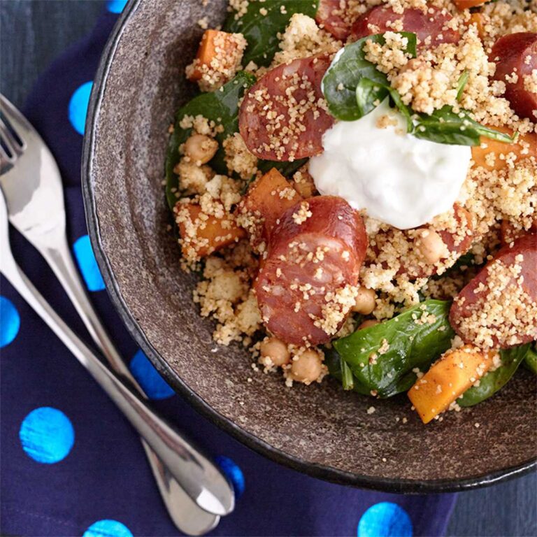 Chorizo pumpkin with couscous and spinach salad in a bowl with dollop of yogurt