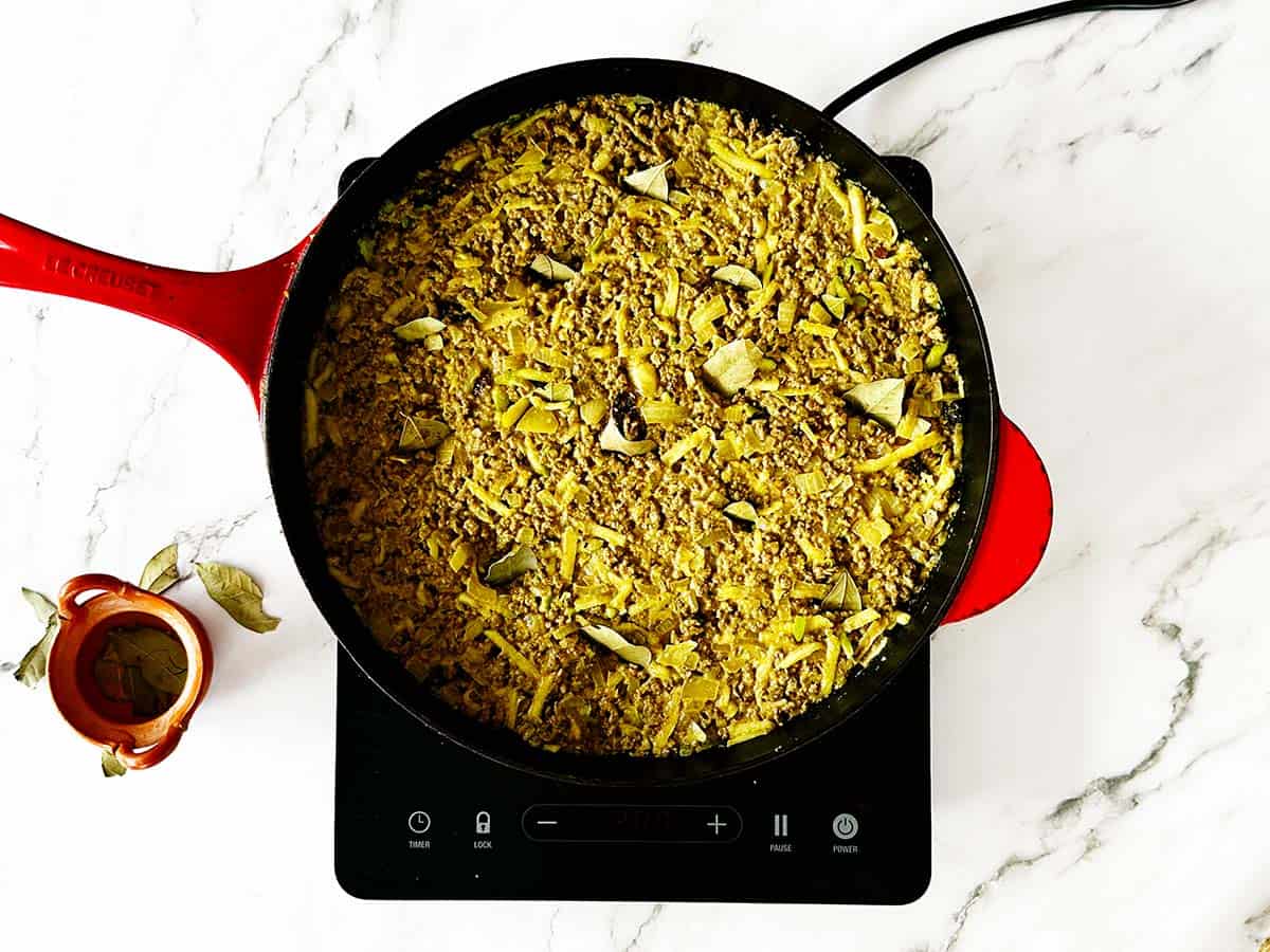 Bay leaves pressed upright into smoothed Cape Malay bobotie mince before baking