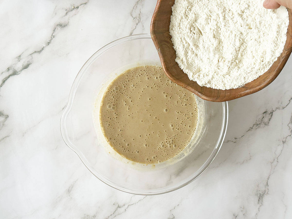 Adding flour gradually to Malva pudding batter in bowl