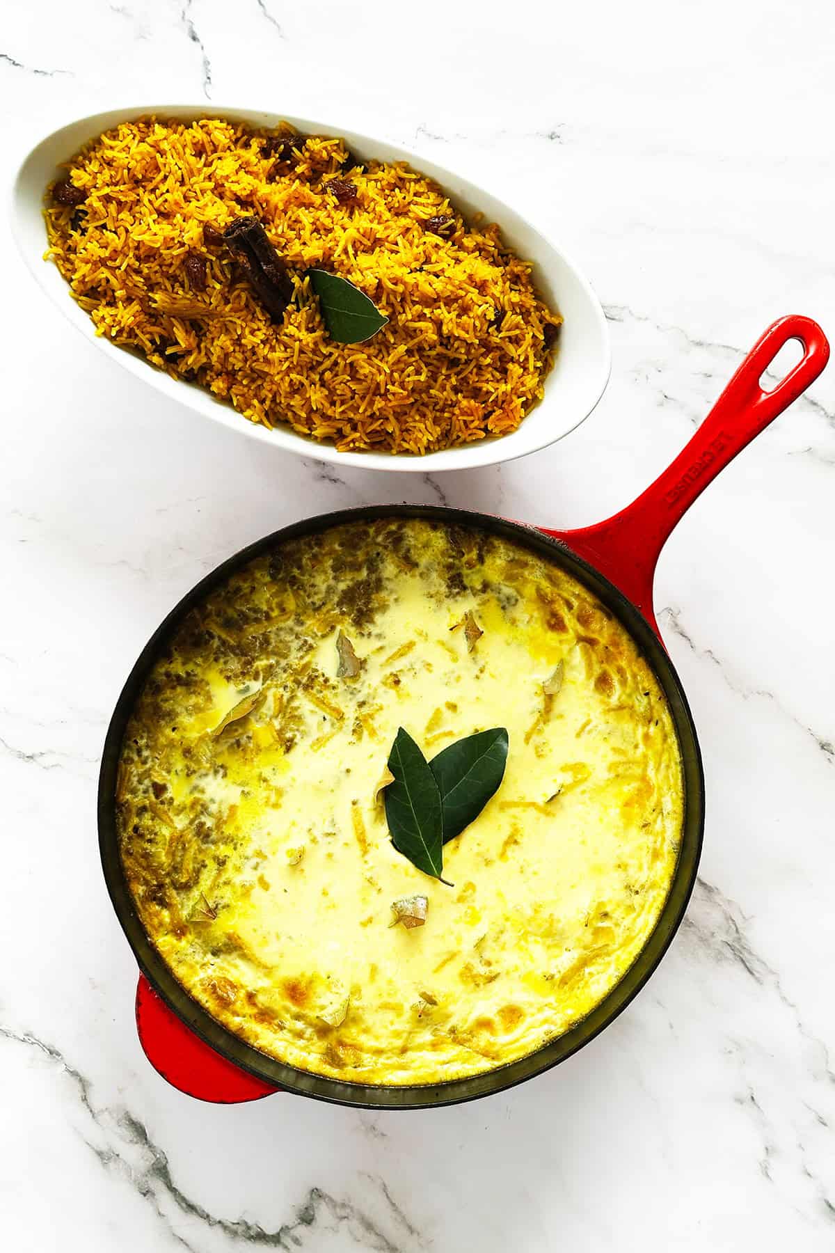 Bobotie in red skillet with yellow rice served on side