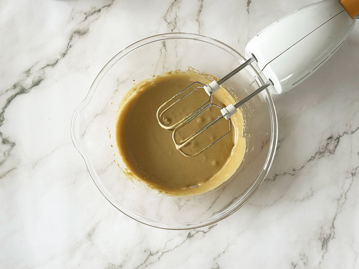 Creamed egg and brown sugar mixture for Malva pudding batter with electric hand mixer