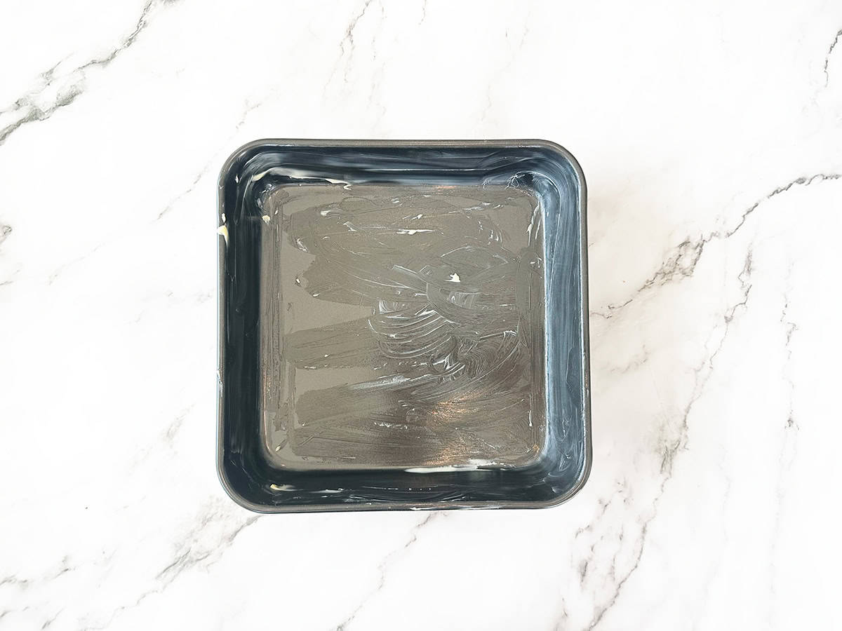 Greased 20cm (8-inch) square baking dish prepared for Malva pudding