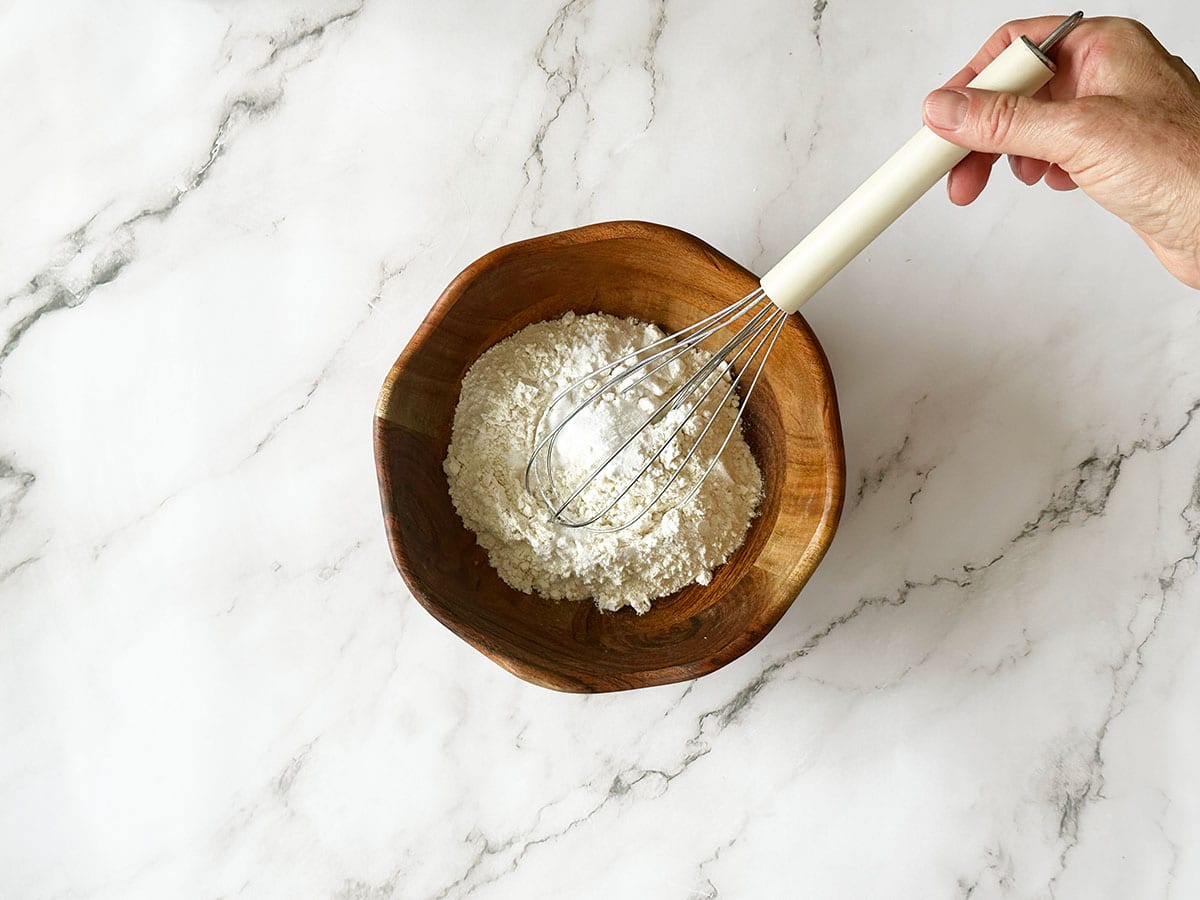 Dry ingredients whisked in wooden bowl for Malva pudding batter