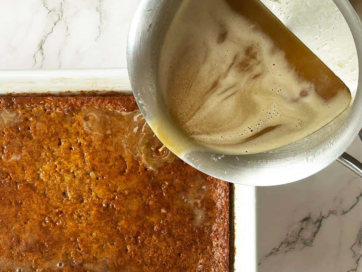 Pouring hot sauce over freshly baked Malva pudding in baking dish