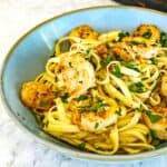 Courgette prawn pasta, served in a blue bowl with caramelised prawns, courgette, and parsley.