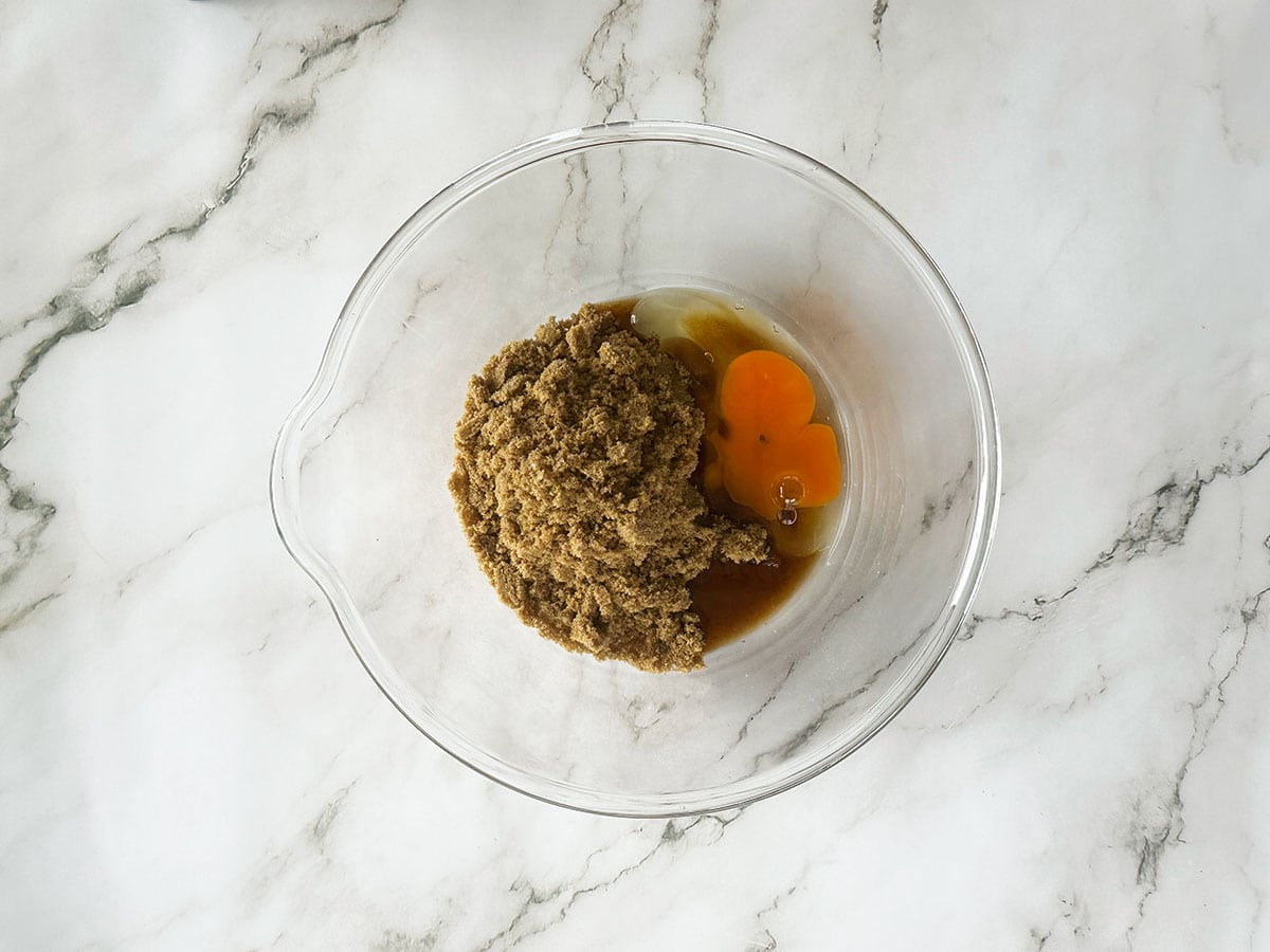 Brown sugar and egg in glass bowl for Malva pudding batter