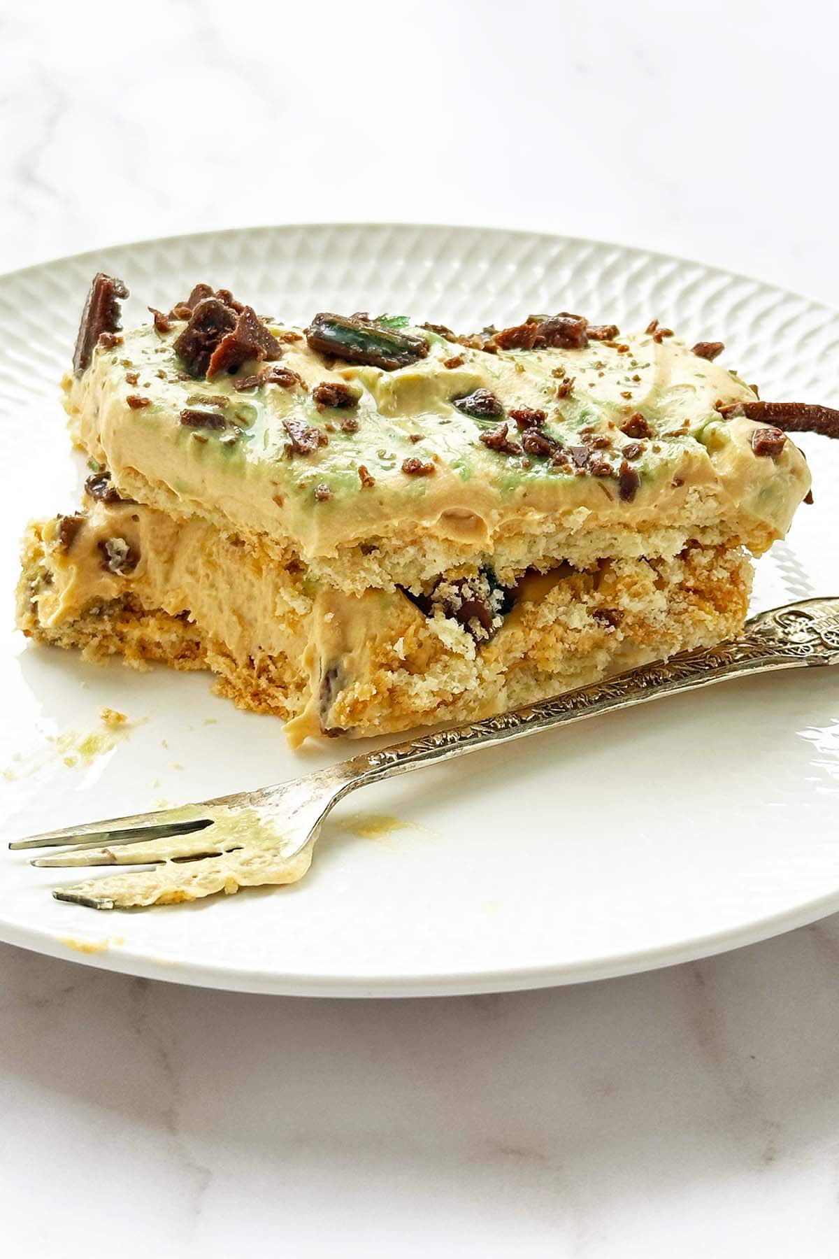 Slice of peppermint crisp tart on a small plate with a bite taken out and a dessert fork