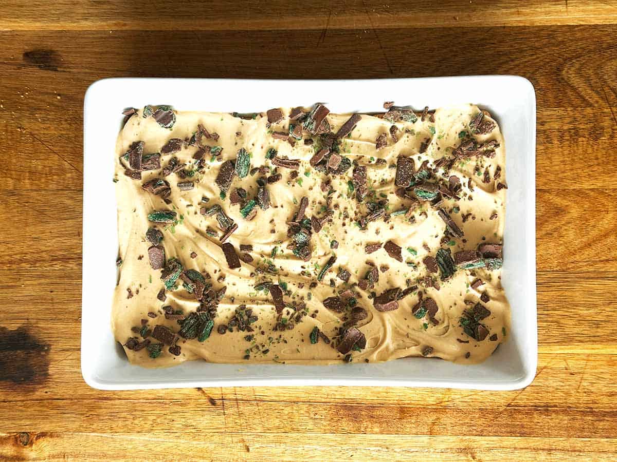 Sprinkling crushed Peppermint Crisp over caramel cream layer for peppermint crisp tart