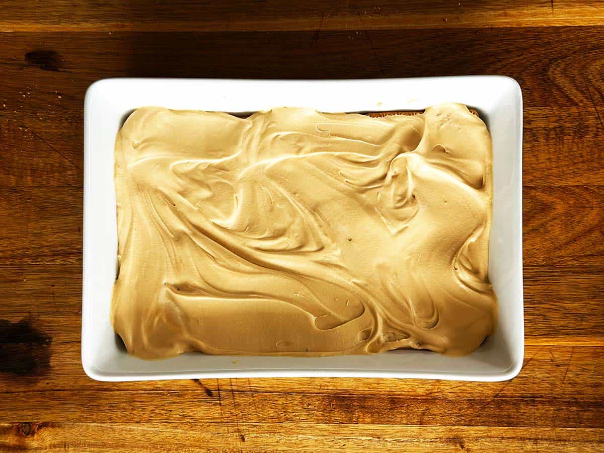 Spreading caramel cream evenly over Tennis biscuits for peppermint crisp tart