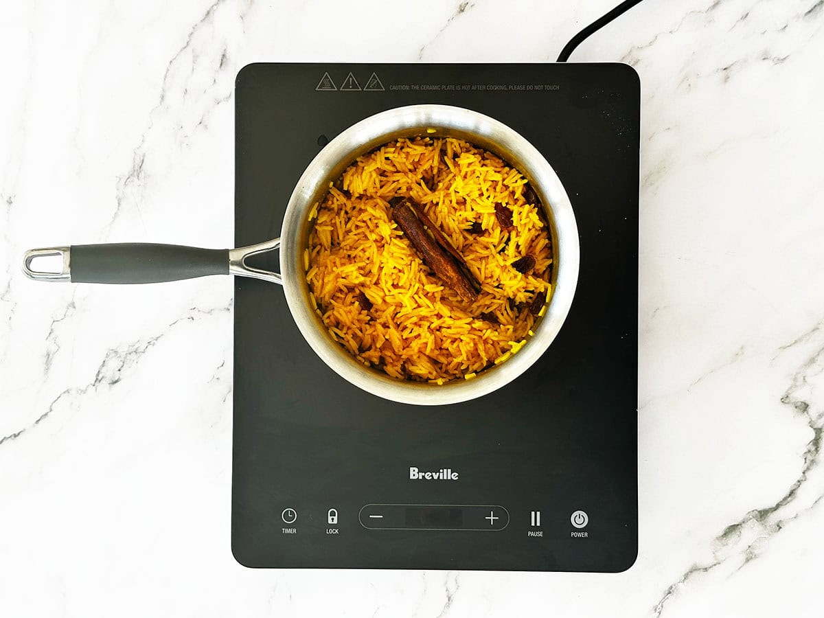 Fluffing rice with fork in pot after cooking