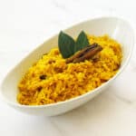 South African yellow rice (geelrys) with raisins in white bowl with cinnamon stick