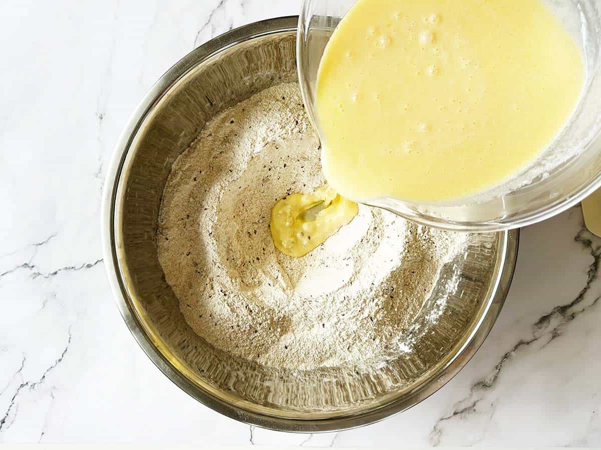 Pouring wet ingredients into well for whole wheat rusk recipe