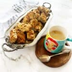 A stack of golden all bran rusks on a silver server with a cup of coffee
