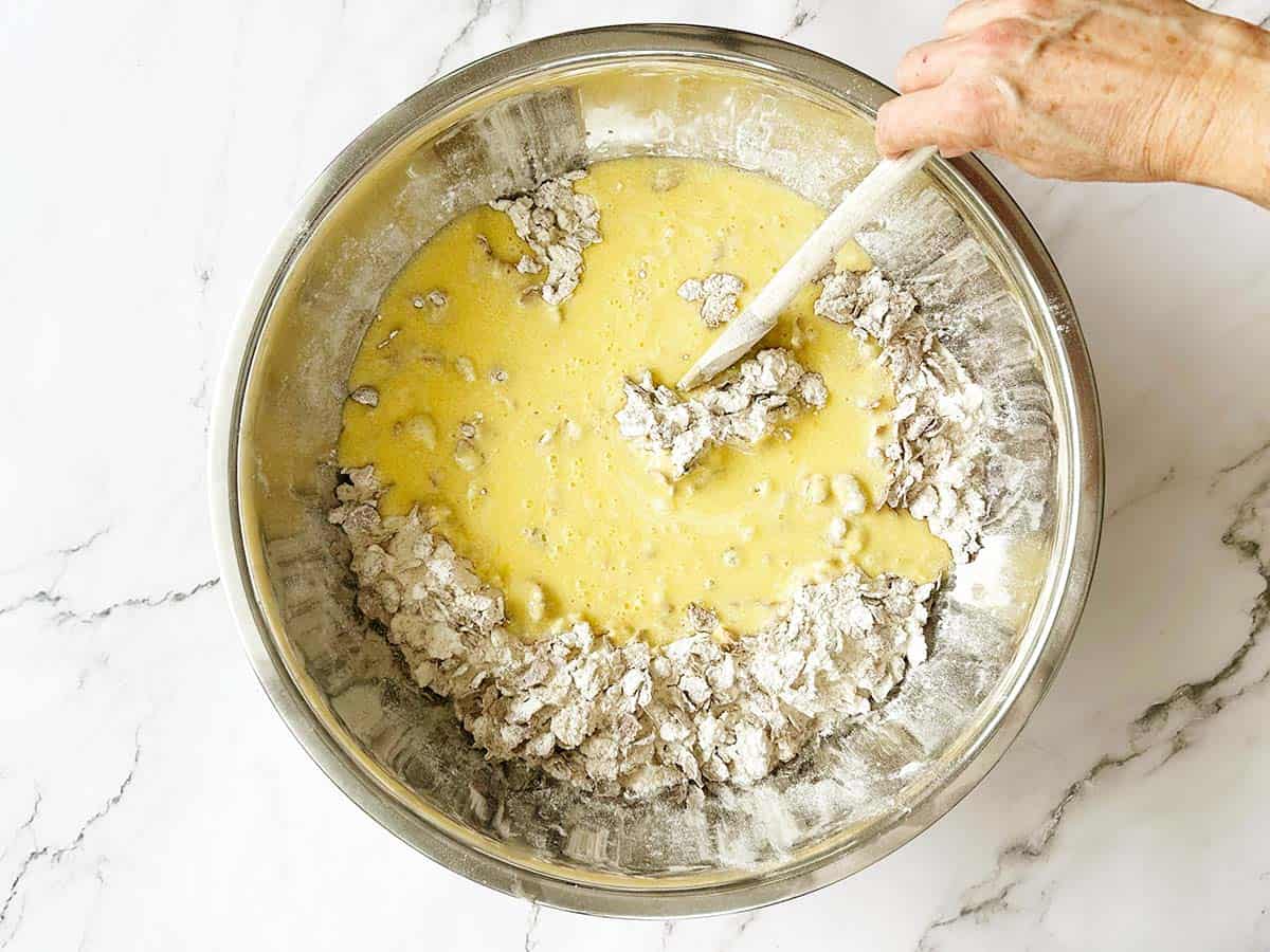 All bran rusk wet ingredients halfway mixed into the dry ingredients in a large bowl
