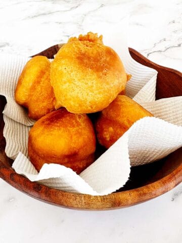 Golden fried vetkoek without yeast piled in a bowl, crisp outside and soft inside