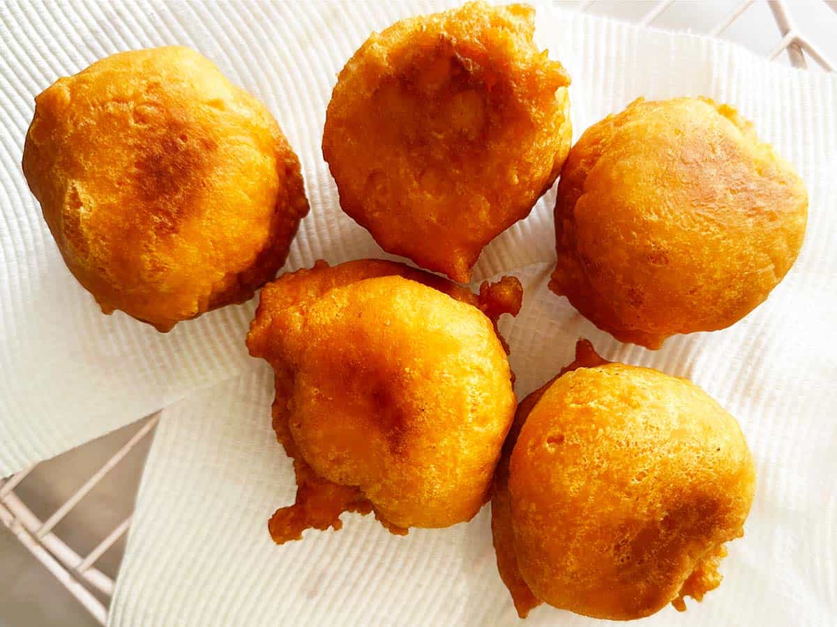 Five golden 3 ingredient vetkoek draining on paper towel