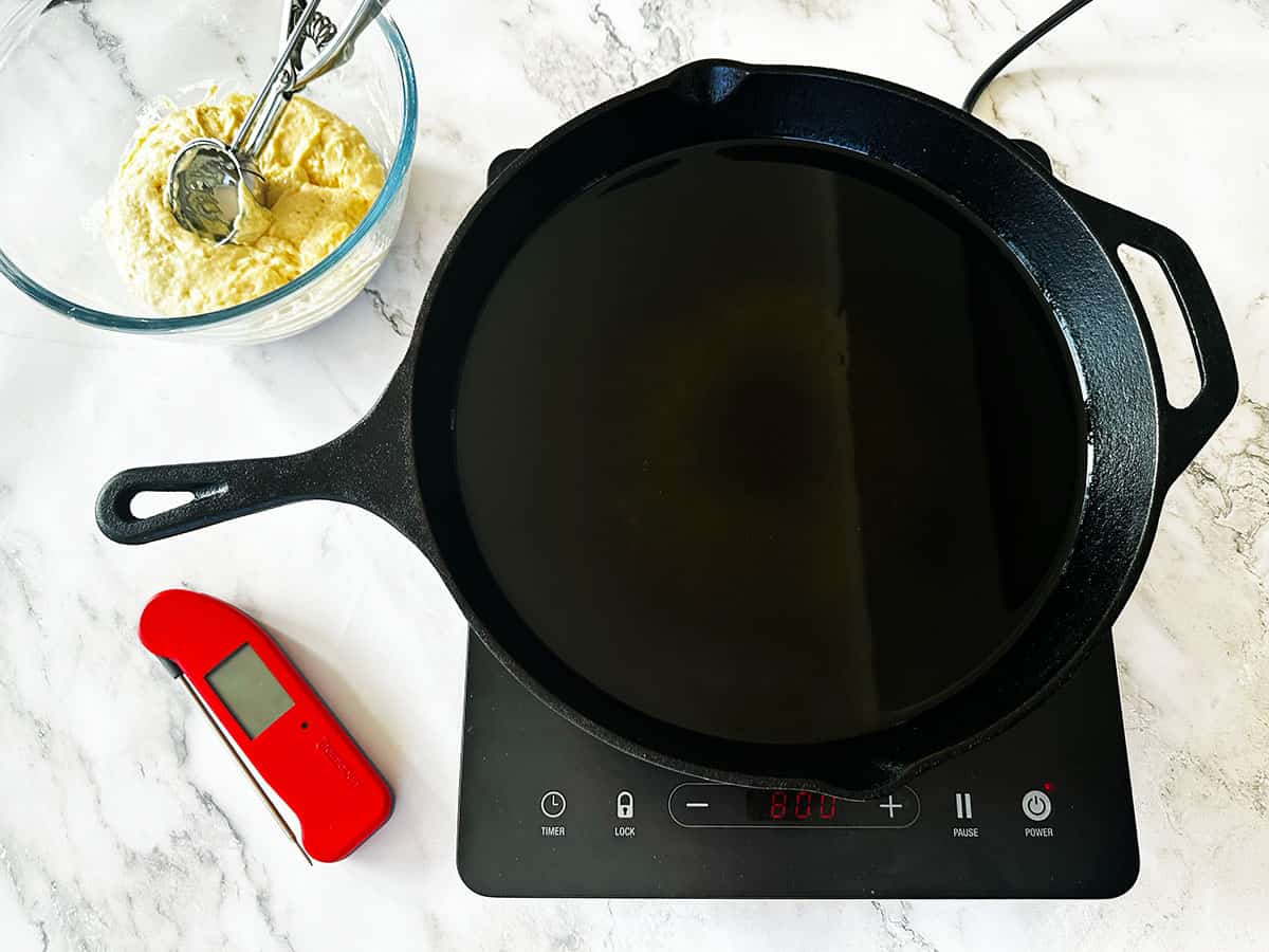 Oil heated to 180°C (350°F) using a thermometer with the ice cream scoop in the dough ready to scoop the vetkoek dough in hot oil